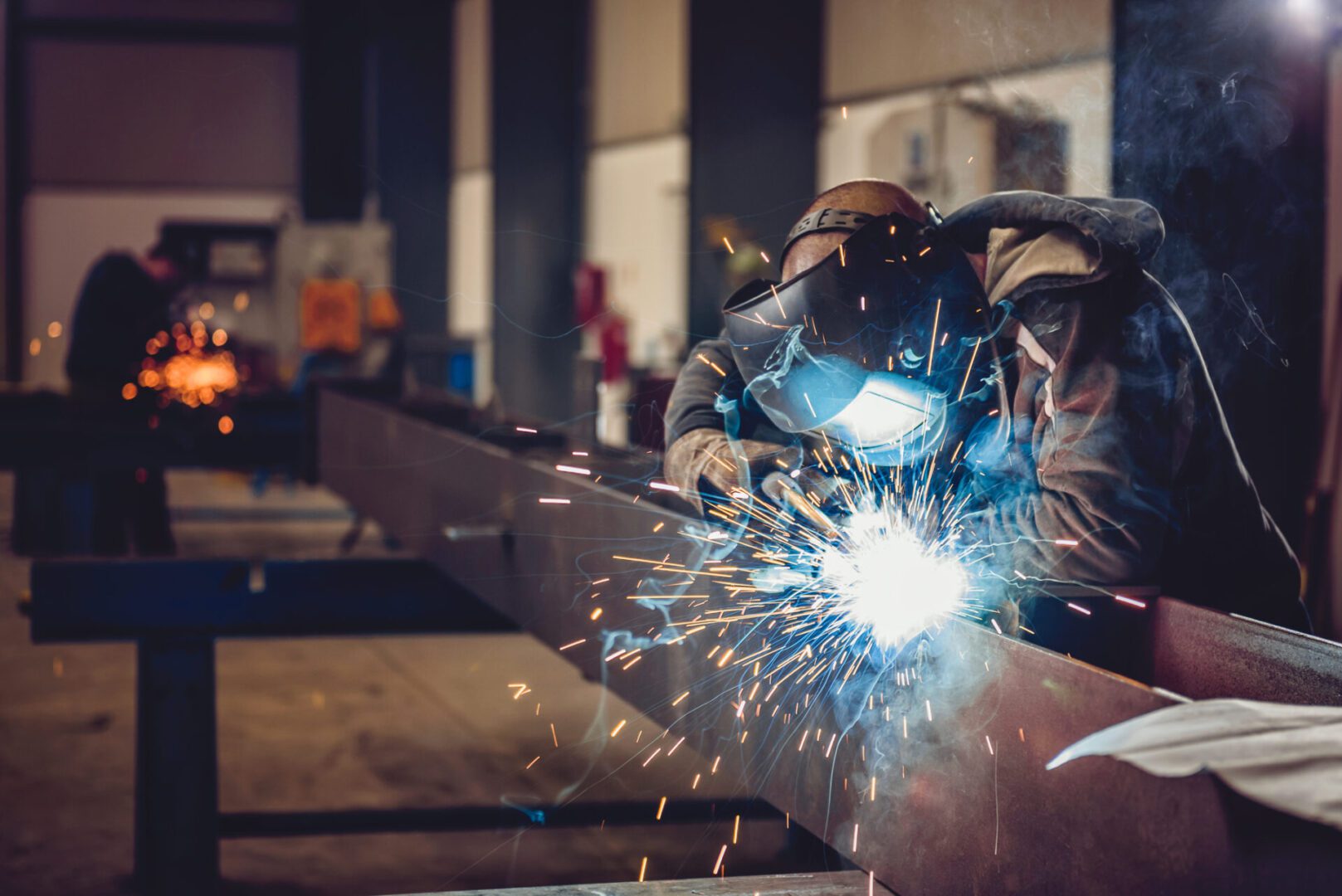 Welder working with sparks in workshop.